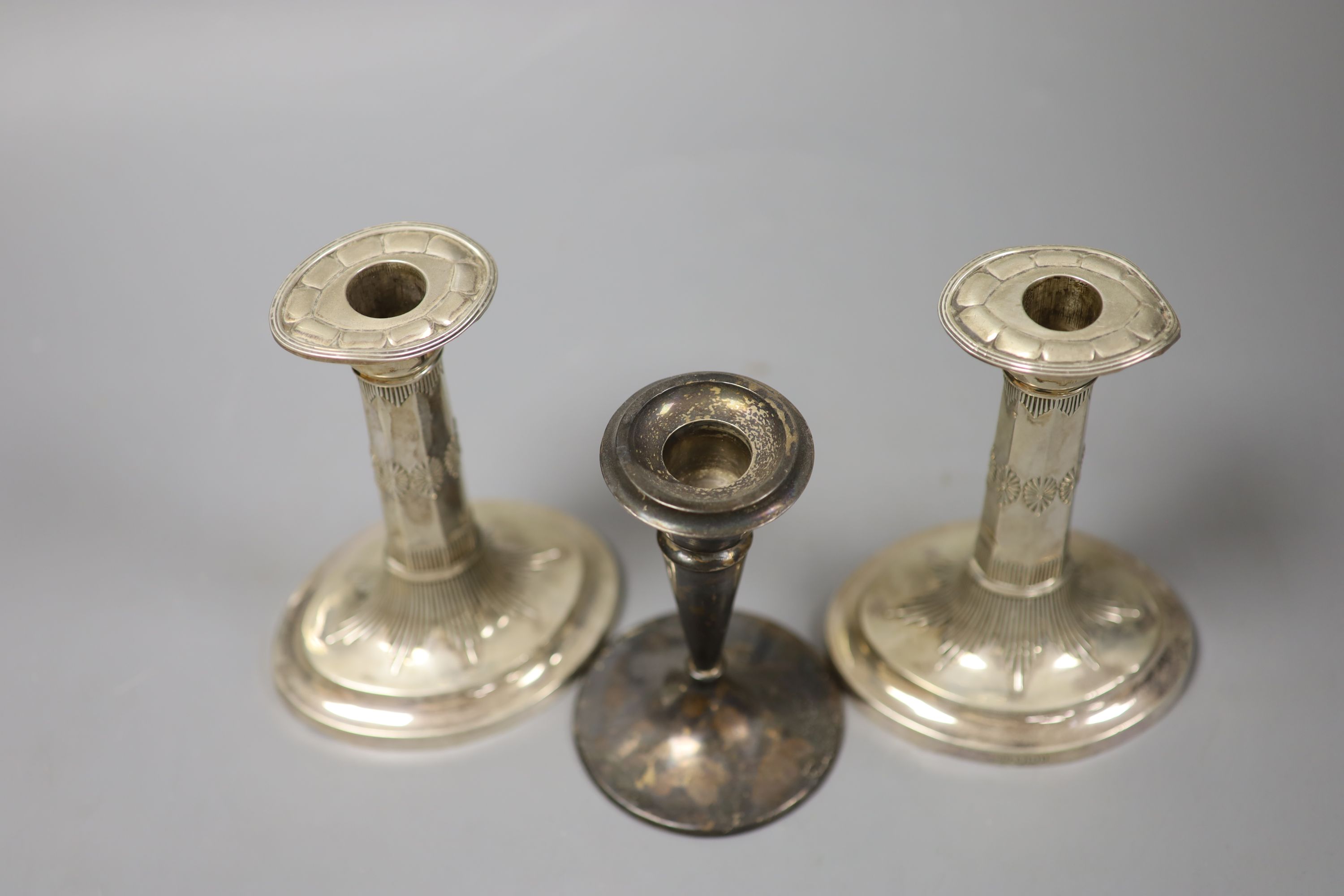 A pair of late Victorian silver dwarf candlesticks, George Howson, Sheffield, 1900, 15.2cm and one other silver candlestick, all weighted.